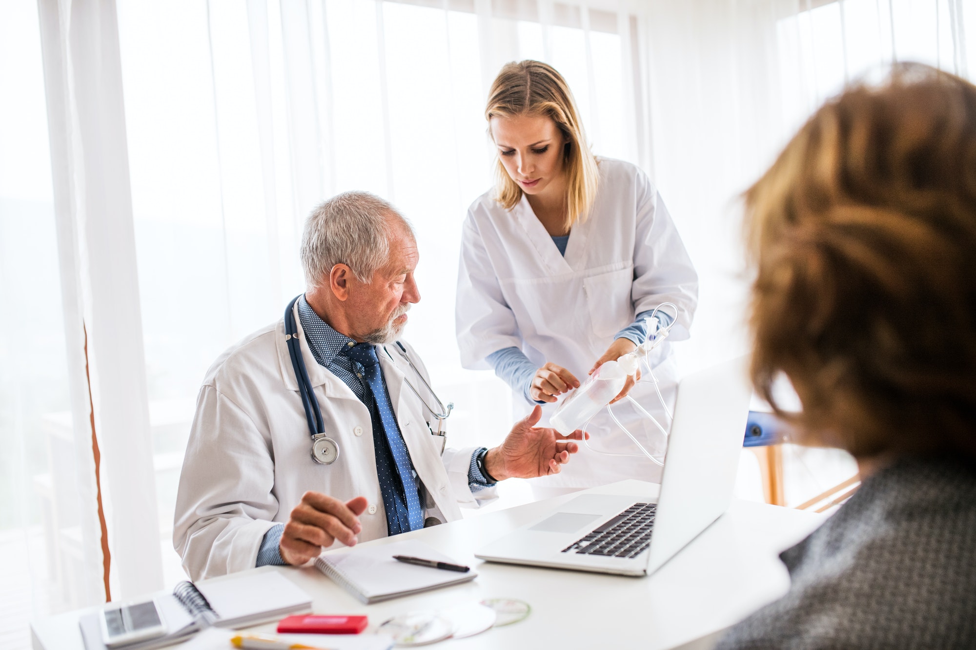 Senior doctor examining a senior woman in office.